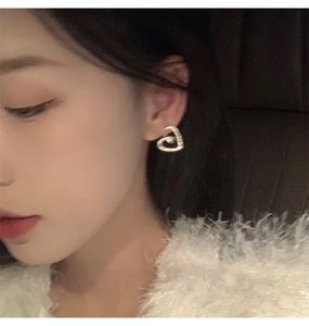 Gros plan de boucles d'oreilles cœur en zircone dorée portées par un mannequin