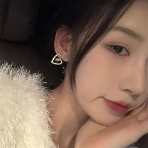 Gros plan d'une boucle d'oreille cœur en zircon étincelant portée par un mannequin