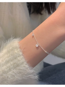 Primer plano de pulsera con colgante de corazón y circonitas en muñeca de mujer