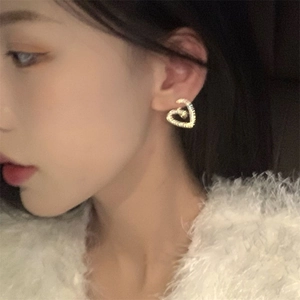 Élégantes boucles d'oreilles cœur dorées avec zircon portées par un mannequin chic