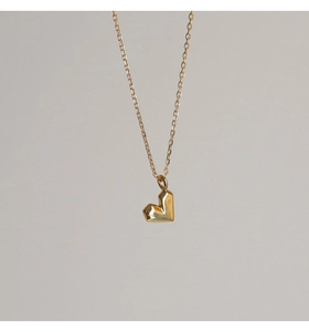 Detailaufnahme des geometrisch facettierten Herzanhängers an einer feinen Goldkette