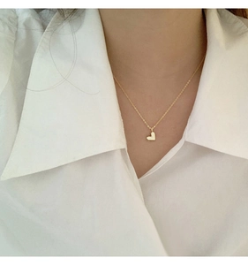 Detail einer minimalistischen goldenen Herzanhänger-Halskette an einem Modell