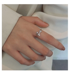 Detailed view of silver bow-knot ring with zircon inlay worn on a female finger