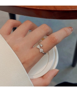 Detail of silver bow ring with sparkling crystals worn on index finger in a cozy setting