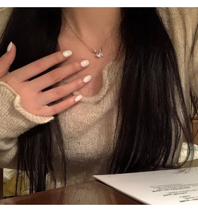 Close-up of a silver bow necklace with zircon stones on a woman's collarbone