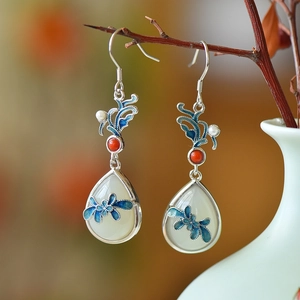 Detailed macro view of white jade drop earrings with blue enamel flower and bird patterns