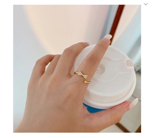 Detail of a sparkling bow-shaped gold ring with small diamonds on a model's finger