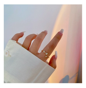 Close-up of golden bow-shaped open ring with sparkling pavé zircons on model's hand