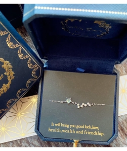 Vue détaillée d'un bracelet étoile en argent avec pierre verte dans son coffret cadeau bleu
