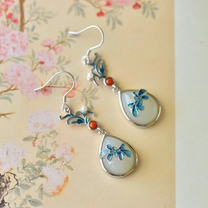 Detail view of teardrop Hetian jade earrings with blue enamel flowers and red beads