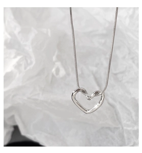 Close-up of a silver hollow heart pendant with a sleek polished snake chain on white paper
