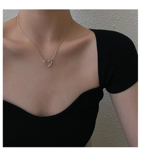Close-up of minimalist hollow heart pendant necklace worn on a black knit top
