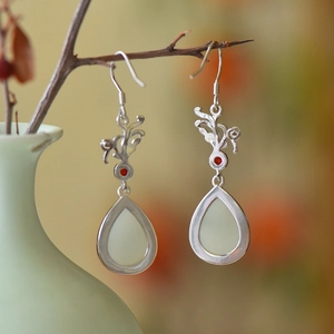 Macro shot of Hetian jade drop earrings with silver floral filigree and red stones