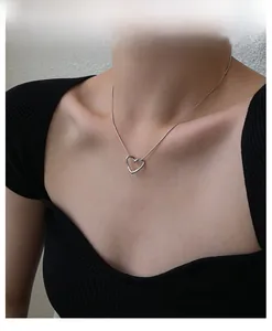 Detail shot of a minimalist silver heart pendant necklace on a black outfit