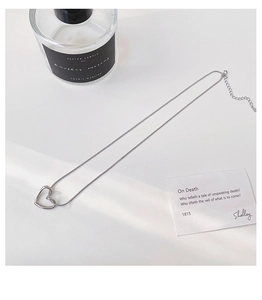 Detailed view of silver hollow heart pendant necklace with adjustable chain on white backdrop