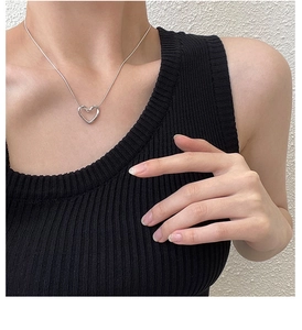 Close-up of minimalist silver hollow heart necklace on model with sleek snake chain