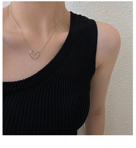 Detail view of a polished silver hollow heart pendant necklace on a female model