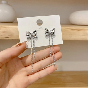 Elegant silver bow tassel earrings with micro-paved rhinestones on a white card