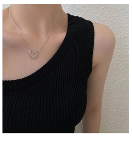 Close-up of minimalist silver hollow heart necklace on a model wearing black top
