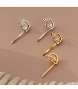 Gros plan de boucles d'oreilles en forme de D en or et argent avec pierres cristallines