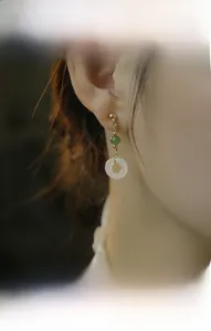 Dettaglio di modella che indossa orecchini vintage in giada con metallo dorato e pietra