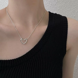 Modern hollow heart pendant necklace in silver with delicate snake chain on a model