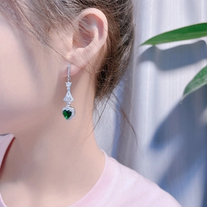 Eleganti orecchini pendenti in argento con cuore di zircone verde indossati da una modella