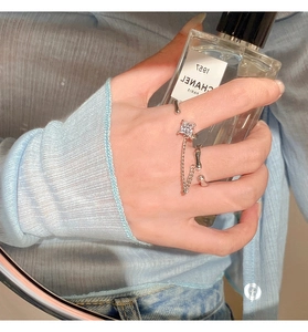 Detailed view of adjustable silver chain ring with square zircon worn on finger