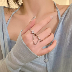 Detailed close-up of a silver chain ring with zircon stone worn on a blue cardigan sleeve