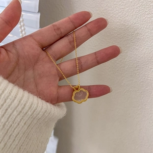 Goldene Ruyi-Halskette mit weißem Jademedaillon in der Hand eines Models gezeigt