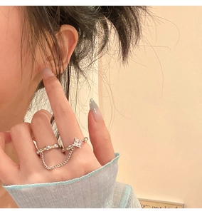 Detail of silver chain ring with square zircon stone and wavy texture on model's hand