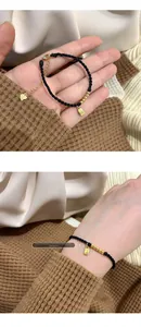 Detail of black woven rope bracelet with gold Fu pendant and S925 silver tag