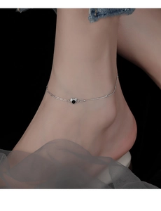 Detail of silver anklet with black heart pendant on asymmetrical snake and link chains