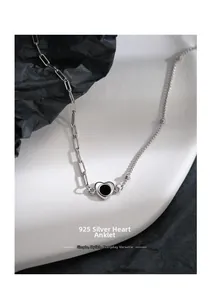 Detail of S925 sterling silver heart anklet with paperclip chain on a white ceramic plate