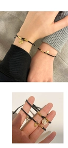 Close-up of black braided bracelets with gold Fu character charms for couples