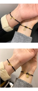 Detailed macro of handwoven black cord bracelet with gold Fu charm and rectangle tag