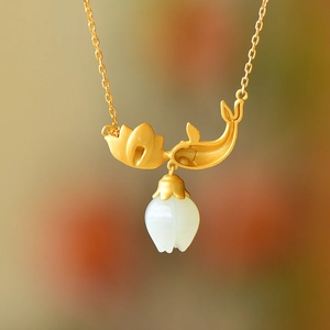 Macro shot of gold-plated lotus necklace with koi pendant and white jade flower bud charm
