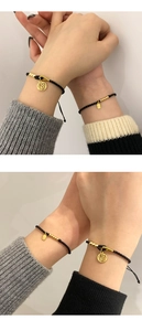 Close-up of woven black couple bracelets featuring a golden Fu charm and beads