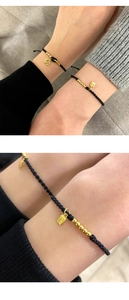 Detailed macro view of woven black cord bracelet with gold Fu charm and metallic beads