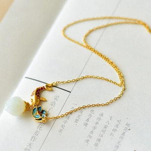 Retro Chinese style necklace with gold koi fish and jade lotus pendant on a poetry book