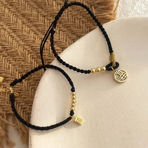 Pair of black woven bracelets with golden Fu character pendants for couples