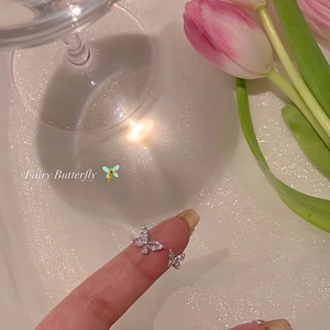 Macro shot of silver butterfly ring with sparkling zircons on a soft pink floral background