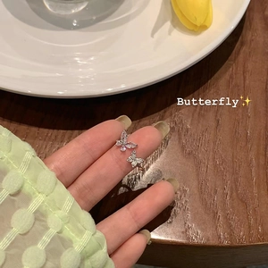 Detail of silver butterfly open ring with sparkling cubic zirconia on a female finger