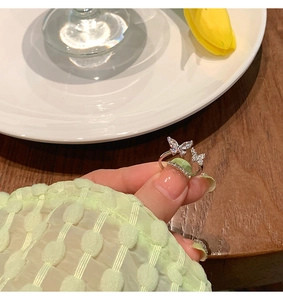 Detailed close-up of a silver butterfly ring with shimmering diamonds on light green fabric
