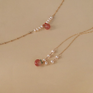 Gros plan d'un collier de perles avec pendentif pêche rose et détails de feuilles