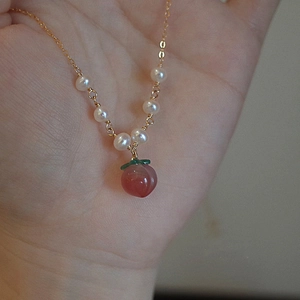 Collier élégant en perles dorées avec pendentif pêche rose et détail de feuille verte