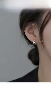Model wearing silver hollow heart-shaped stud earring with minimalist metal design
