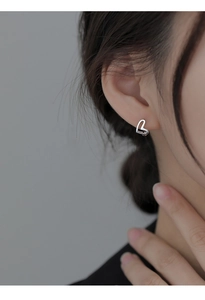 Close-up of heart-shaped hollow earrings in sterling silver worn on ear
