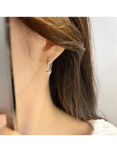 Close-up of a silver earring with a triangle-cut clear zircon on a model's ear
