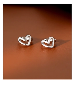 Close-up of silver hollow heart-shaped earrings on a brown textured leather surface